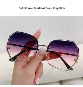 Close-up of geometric gold metal frame sunglasses with gradient deep grey pink lenses