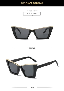 Detail of black cat eye sunglasses with golden metal top bar inlay and dark grey lenses