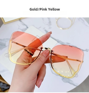 Detail of rimless gold sunglasses featuring pink and yellow gradient tinted lenses