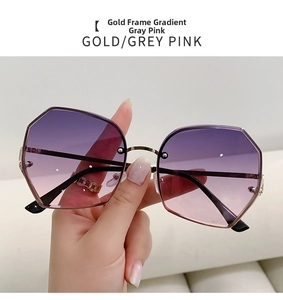 Detailed close-up of gold geometric sunglasses with gradient pink lenses held by hand