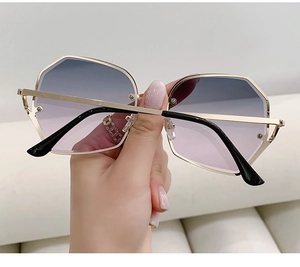 Detail of geometric metal frame sunglasses with gradient blue-purple lenses and gold temples