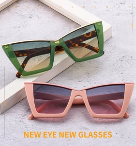 Detail of oversized cat-eye sunglasses in green and pink with gradient lenses