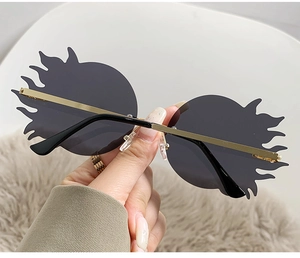 Détail de lunettes de soleil flamme sans monture avec verres gris et branches dorées