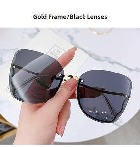 Detail of rimless sunglasses with gold metal bridge and dark grey lenses on marble