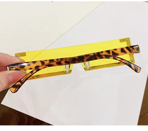 Détails des verres rectangulaires jaunes et branches léopard sur lunettes de soleil