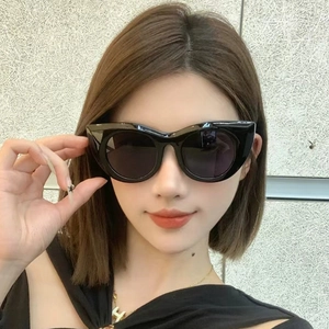 Close-up of black cat-eye sunglasses with thick glossy frames and dark UV lenses