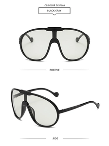 Close-up of black oversized aviator sunglasses with gray lenses and side profile view