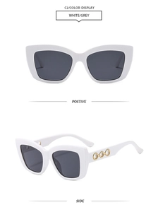 Detail of white cat eye sunglasses with golden triple-ring metal hollow temples and grey lenses