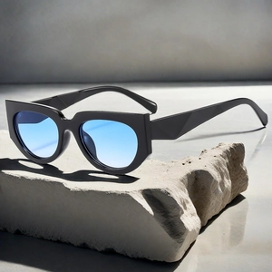 Detail of chunky black square frame sunglasses with blue gradient lenses on stone