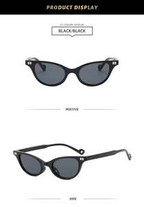 Close-up of black cat-eye sunglasses with silver B-shaped metal details and dark lenses
