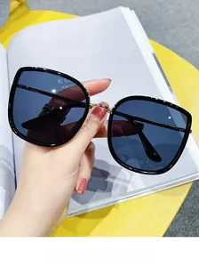 Detail of square oversized black sunglasses with gold bridge on a lifestyle background