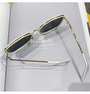 Detail of cream oversized sunglasses with gold metal temples on a fashion magazine