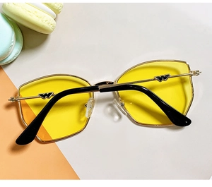 Detail of kids UV sunglasses with yellow transparent lenses and golden W-shaped hinges