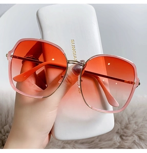 Détail de lunettes de soleil en métal avec verres dégradés roses et étui blanc