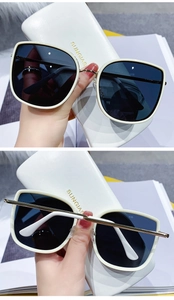 Detail of white oversized sunglasses with gold metal bridge and leather case