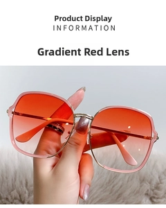 Détail de lunettes de soleil en métal avec verres dégradés rouges tenues à la main