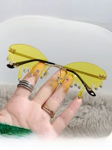 Détail de lunettes de soleil sans monture jaune goutte d'eau avec strass et monture dorée