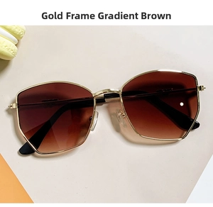 Close-up of gold metal frame sunglasses with gradient brown lenses on paper background