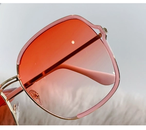 Gros plan sur les lunettes de soleil en métal doré avec verres dégradés rouge et rose