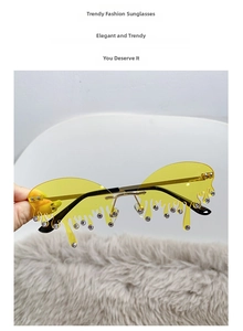 Détail de lunettes de soleil sans monture jaunes en forme de larme avec strass et branches dorées
