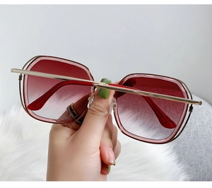 Detail of reddish-brown gradient lenses and gold metal frame of oversized sunglasses