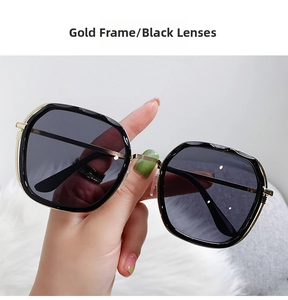 Close-up of gold metal frame sunglasses with dark grey lenses on white plush
