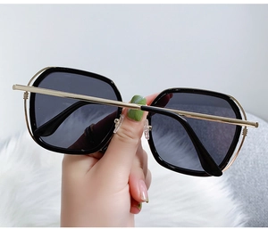 Detail of oversized retro sunglasses with black frames and gold metal temples