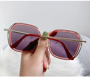 Detail of red transparent oversized sunglasses with purple gradient lenses and metal hinges
