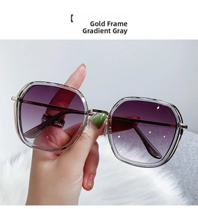 Detail of oversized geometric sunglasses with gold frames and gradient grey lenses