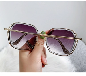 Detail of oversized sunglasses with purple gradient lenses and double-layered gold frames