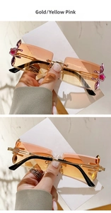 Detail of gold rectangular sunglasses with yellow-pink gradient lenses and floral rhinestones