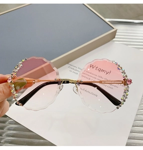 Detail of rimless round sunglasses with pink gradient lenses and floral rhinestone accents