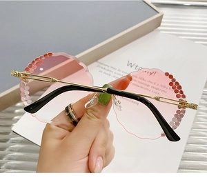 Detail of rimless round sunglasses with pink gradient lenses and floral rhinestone accents