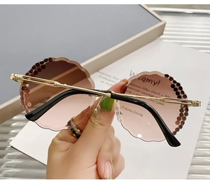 Close-up of rimless round sunglasses with scalloped gradient lenses and rhinestone accents