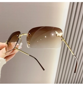 Close-up of frameless gradient sunglasses featuring crystal butterfly detail and gold metal arm