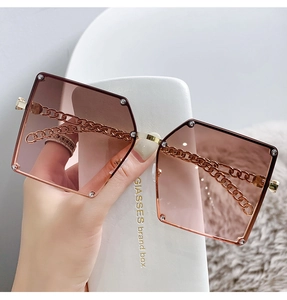 Detail view of gradient brown sunglasses lens with elegant gold chain arm decoration