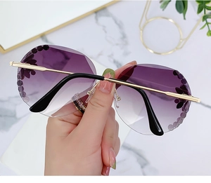 Close-up of purple gradient rimless sunglasses with floral crystal accents and gold stems
