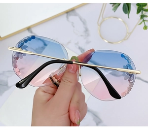 Detail of rimless gradient lenses featuring blue and pink floral dots and gold metal temples