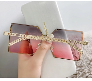 Detail of oversized square sunglasses with purple gradient lenses and gold chain temples