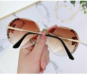 Detail of rimless round sunglasses with brown gradient lenses and flower petal accents