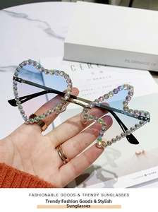 Close-up of rimless heart-shaped sunglasses with colorful rhinestones and blue gradient lens