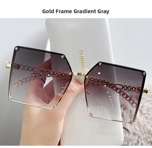 Detail of oversized gold metal sunglasses with chain temples and gradient gray lenses