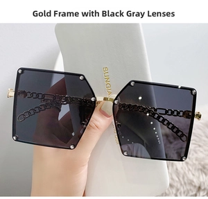 Close-up of oversized metal sunglasses featuring gold chain temples and rhinestone details
