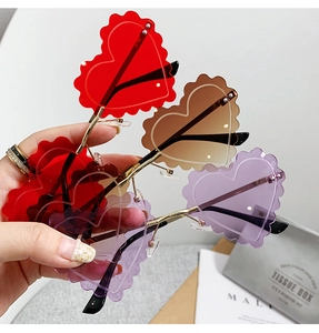 Three colorful heart-shaped rimless sunglasses with wavy edges and gold metal frames