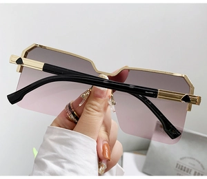 Dettaglio occhiali da sole rimless oversize con lenti sfumate rosa e stanghette dorate
