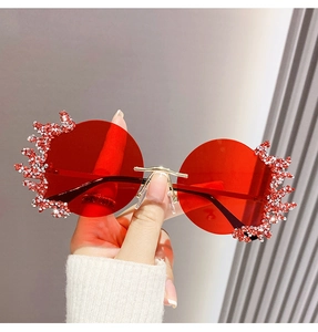 Détail de lunettes de soleil rondes rouges sans monture avec strass et bague assortie