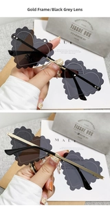 Close-up of wavy edge heart-shaped sunglasses with gold frame and black grey lenses
