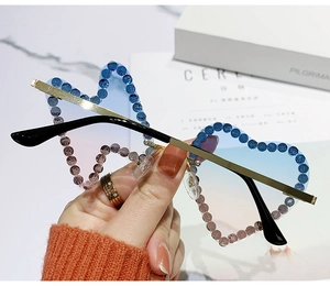 Close-up of rimless heart-shaped sunglasses with gradient lenses and blue rhinestones