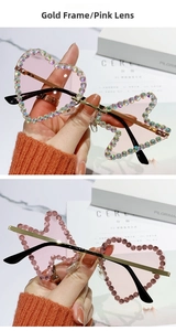 Detail of rimless metal sunglasses with pink lenses and rhinestone butterfly heart design