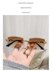 Detail of gold snake-textured temples on rimless sunglasses with brown gradient lenses